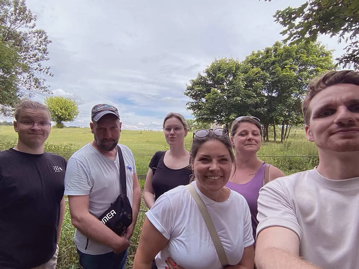 Gruppe von Menschen lachen in die Kamera im Hintergrund eine Wiese und Bäume